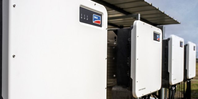 Die Wechselrichter sind in einer Reihe angeordnet, gut sichtbar mit dem SMA-Logo auf der Vorderseite, unter einem Dach.