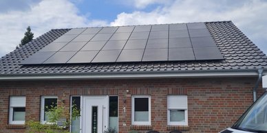 Ein modernes Haus mit einem schrägen Dach, das mit mehreren Solarpanelen bedeckt ist, unter einem klaren Himmel.