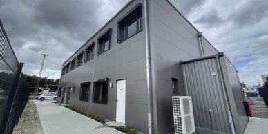 Das Gebäude hat eine industrielle Ausstrahlung, mit einem WC-Schild an der Tür und einer Klimaanlage an der Wand.