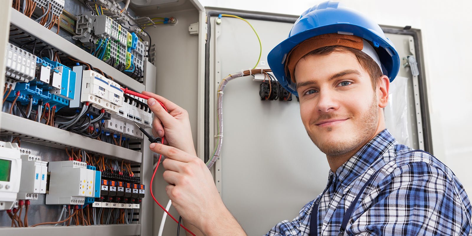 Ein junger Elektroniker überprüft einen Verteilerkasten