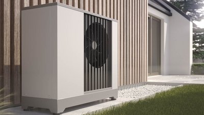 Die Außeneinheit einer Wärmepumpe ist in einem modernen Garten platziert, mit einem klaren Blick auf die Holzverkleidung im Hintergrund.